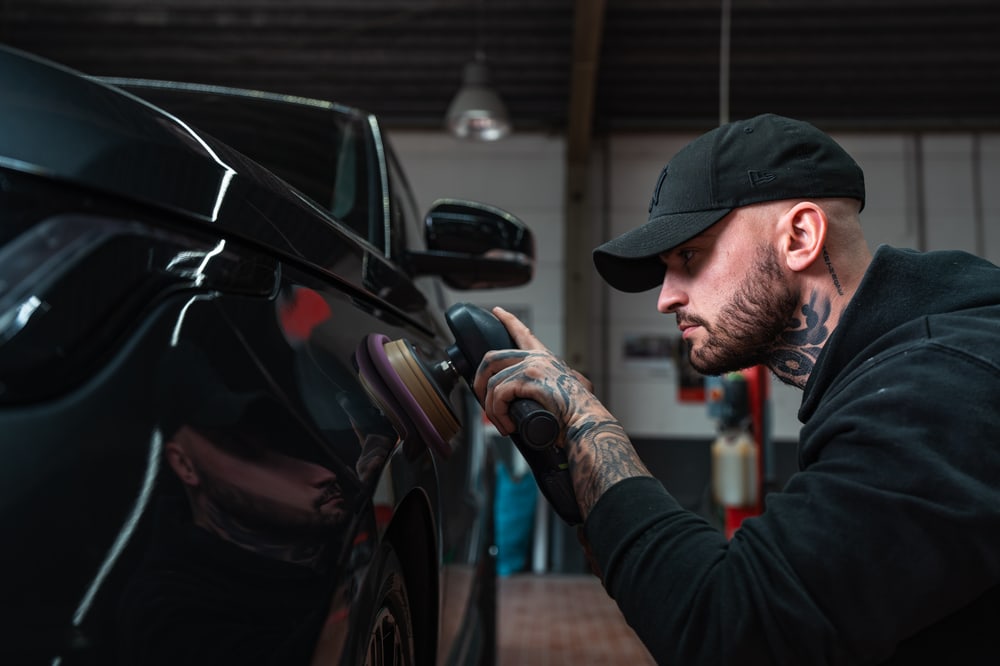 Mitarbeiter beim Polieren einer schwarzen Fahrzeugkarosserie